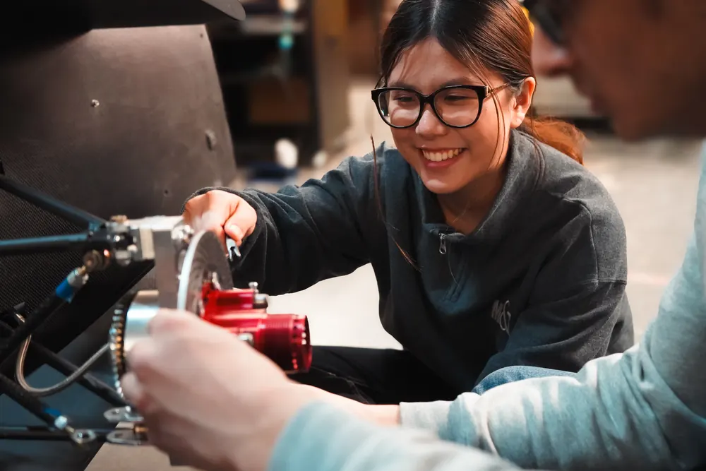 A team member smiles while fitting a red component to the car